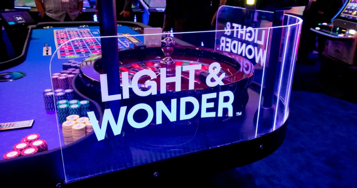 Light & Wonder 展台与轮盘桌的品牌灯箱近景，展示公司标识与赌场设备