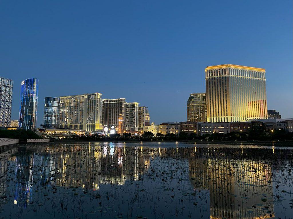 傍晚时分的澳门路氹城度假区天际线与湖面倒影，多家综合度假村灯光亮起，体现第三季度博彩业复苏与城市夜景活力。