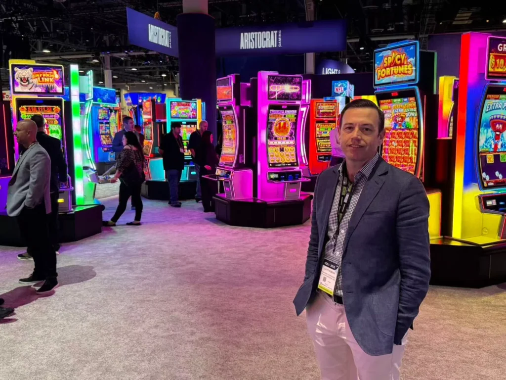 Aristocrat 展台前的产品经理与多款霓虹老虎机机台合影，展示 Dragon Link 系列人气