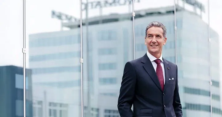 Ainsworth前首席执行官哈拉尔德·诺伊曼身着西装站在总部大楼前的形象照