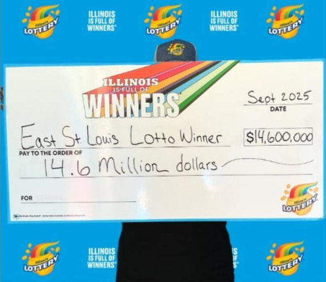 伊利诺伊州乐透宣传背景墙前的中奖彩票展示，印有East St. Louis Lotto Winner
