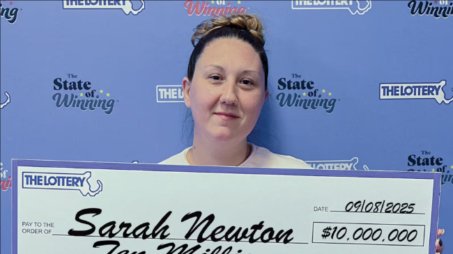 中奖者手持巨额支票在背景板前合影