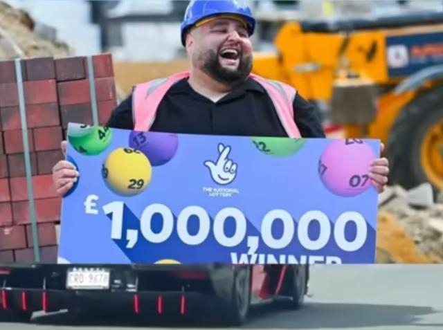 手持“£1,000,000中奖”牌的男子在工地庆祝的近景照片