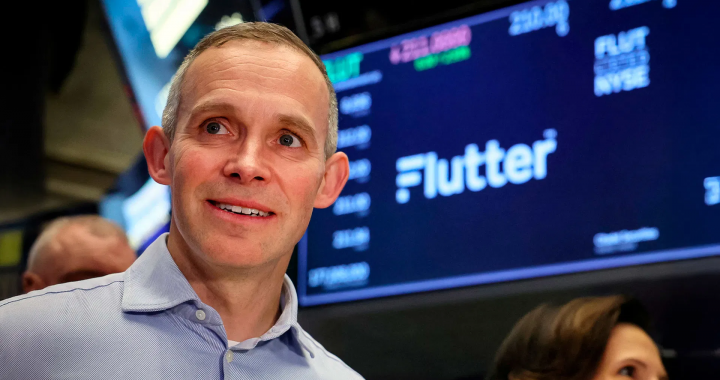 Flutter Entertainment（颤振娱乐）首席执行官彼得·杰克逊（Peter Jackson）在纽约证券交易所，背景可见Flutter标志。