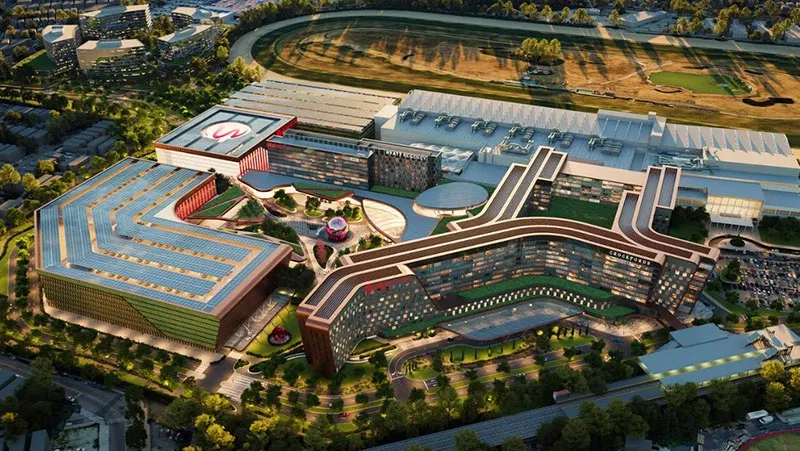 纽约云顶世界（Resorts World New York）扩建后的俯瞰效果图。该渲染图展示了拟建的现代化大型赌场度假村综合体，包括酒店、会议中心和广阔的屋顶绿化及太阳能电池板，旁边是跑马场，体现了云顶集团在皇后区的 55 亿美元重建和改造计划。