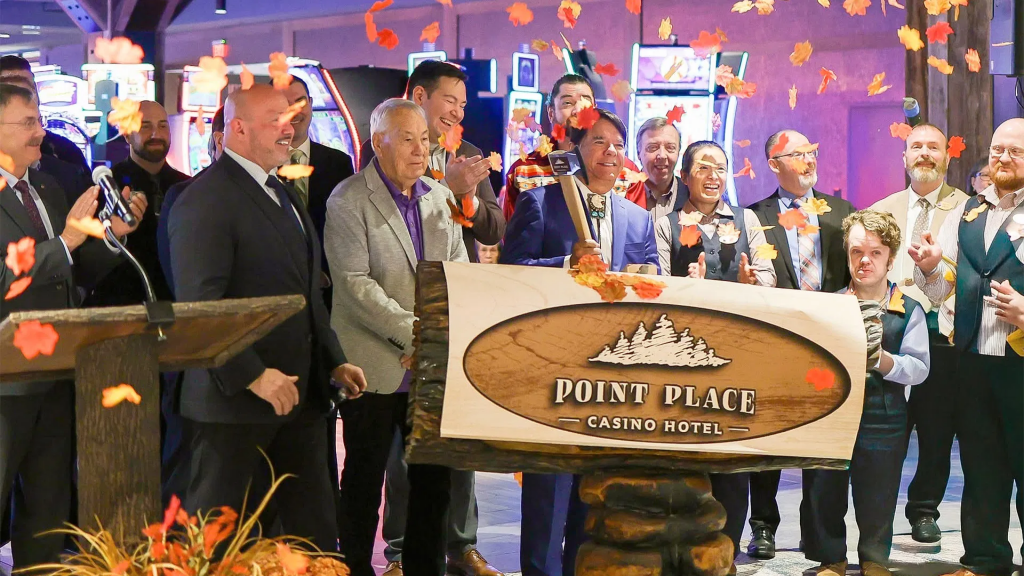 奥奈达印第安民族代表雷·哈尔布里特等领导人手持刻有 Point Place Casino Hotel 标志的木板，在室内举行盛大开幕仪式。现场有彩带和秋叶装饰，庆祝 5000 万美元的扩建工程完工，周围是兴奋的州和地方官员及员工。