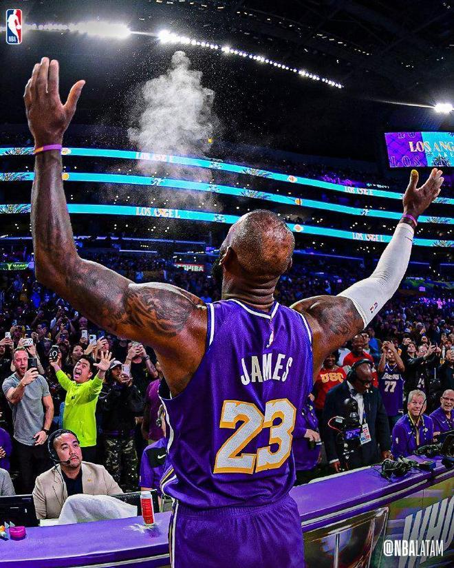 洛杉磯湖人隊球星勒布朗·詹姆斯(LeBron James)背對鏡頭,雙臂高舉向天空拋撒鎂粉或慶祝,背後是激動的觀眾。
