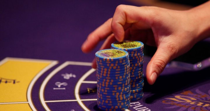 澳门赌场赌桌上玩家整理筹码的特写画面，展示博彩活动与澳门博彩市场相关场景