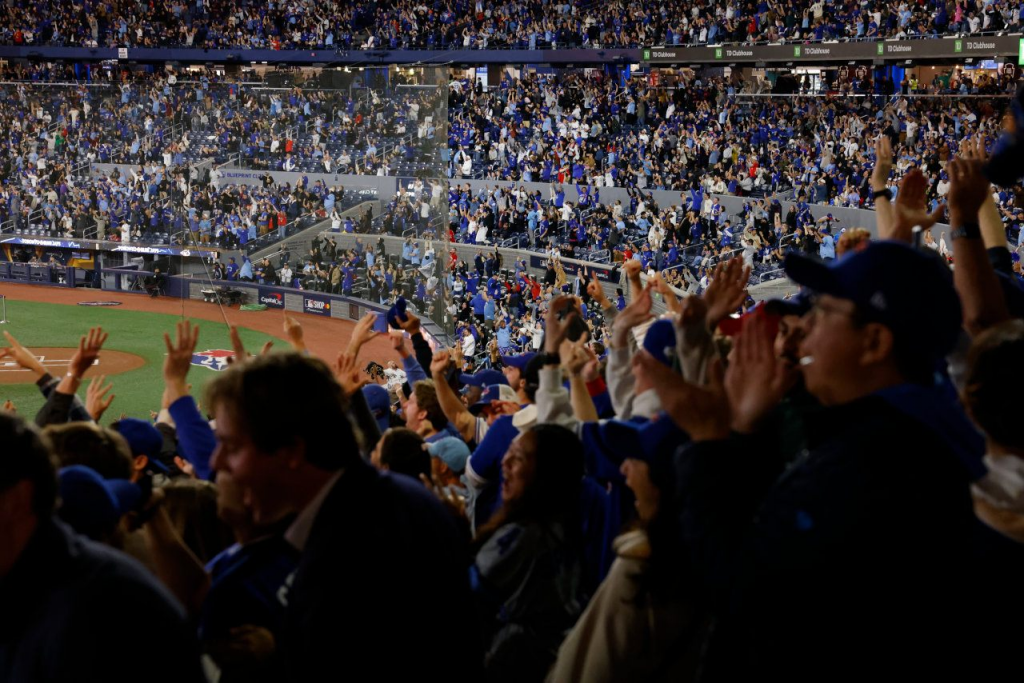 多伦多球场观赛人群高举双手庆祝，蓝鸟队季后赛主场氛围带动本地投注热度。
