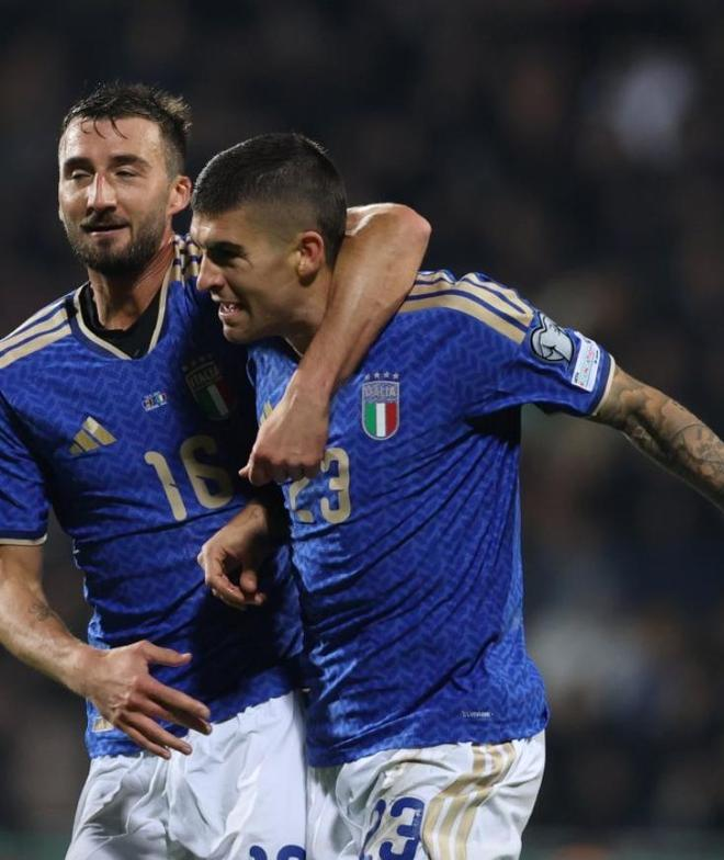 两名身穿蓝色球衣的意大利球员在进球后拥抱庆祝的特写照片