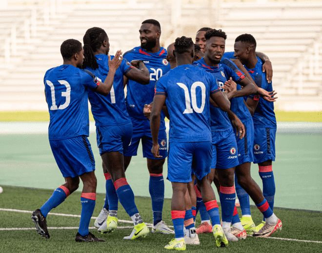 身穿蓝色球衣的海地球员在禁区内相互拥抱庆祝进球