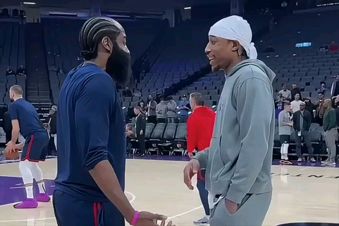 两名球员在赛前场边交流的轻松互动画面。