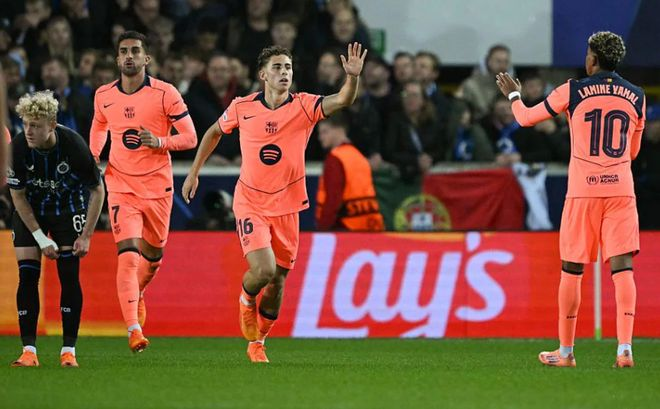 巴萨全粉客场球衣球员高举手臂致意,背景为看台观众。