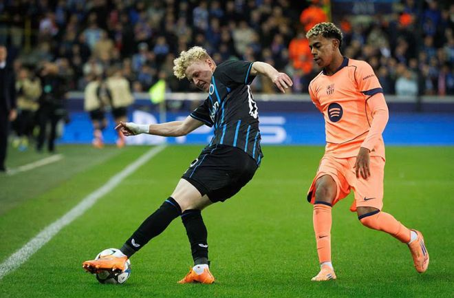 巴萨边锋与布鲁日后卫在边线对抗,双方争抢皮球。