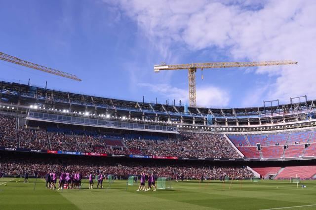 白天的诺坎普改造现场,球队在球场训练,满场观众与大型塔吊同框。