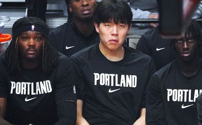 替补席上杨瀚森神情专注坐在队友之间,黑色训练服胸前印有球队英文名称。