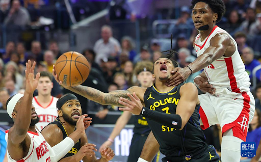 NBA 金州勇士队（黄色球衣）球员与休斯顿火箭队（红色球衣）球员在比赛中激烈争抢篮球，身体对抗十分激烈。此图象征篮球比赛的强度与竞争性，可作为体育新闻或赛事博彩相关报道的配图。