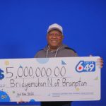 加拿大彩票頭獎得主尼巴爾（汽修工人）在領獎中心，手持一張象徵 500 萬加元巨額獎金的支票，展示他準備用獎金進行投資創業並創造就業機會的喜悅。