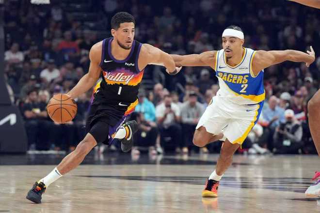 布克持球突破步行者后卫防守的比赛现场照片