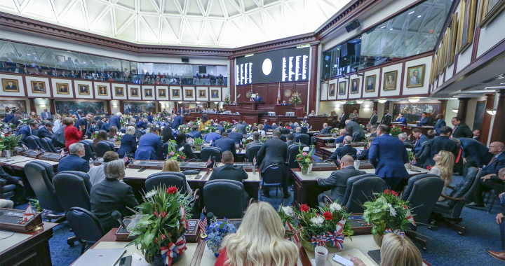 佛罗里达州议会大厅内，议员们正在进行立法会议的场景，背景显示数字屏幕，象征HB 591和HB 189法案的审议进程。