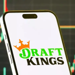 智能手机屏幕显示DraftKings预测市场（DraftKings Predictions）应用程序的标志，背景是金融市场上涨的K线图。