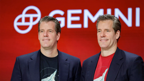 Gemini 交易所创始人泰勒·温克莱沃斯和卡梅隆·温克莱沃斯站在红色的公司 Logo（Gemini）前，身穿西装和印有图案的T恤。