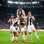 尤文图斯足球队球员身穿黑白条纹球衣，在球场上紧紧相拥，庆祝进球的瞬间。