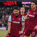 西汉姆联队球员（背号10和15）在比赛中庆祝进球，表情激动，身穿深红色主场球衣。