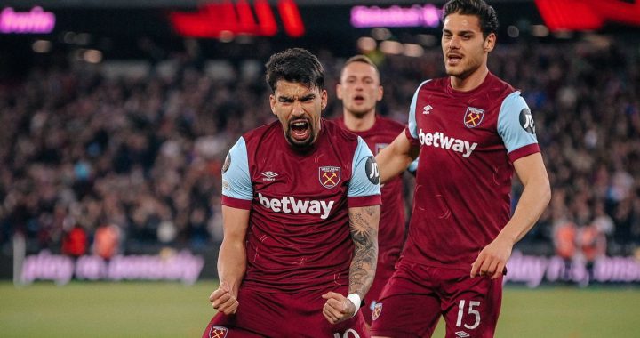 西汉姆联队球员（背号10和15）在比赛中庆祝进球，表情激动，身穿深红色主场球衣。