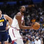 休斯顿火箭队球星凯文·杜兰特（Kevin Durant）身穿白色球衣，在掘金队球星约基奇（Nikola Jokić，15号）的注视下进行罚球。