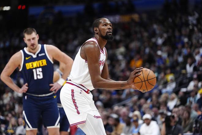 休斯顿火箭队球星凯文·杜兰特（Kevin Durant）身穿白色球衣，在掘金队球星约基奇（Nikola Jokić，15号）的注视下进行罚球。