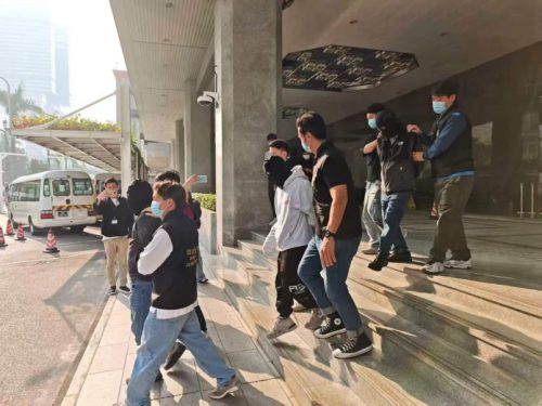 澳门司法警察(司警)逮捕涉嫌非法货币兑换的嫌疑人,嫌疑人被带离建筑物,体现了警方对“赌博用钱”活动的执法行动。