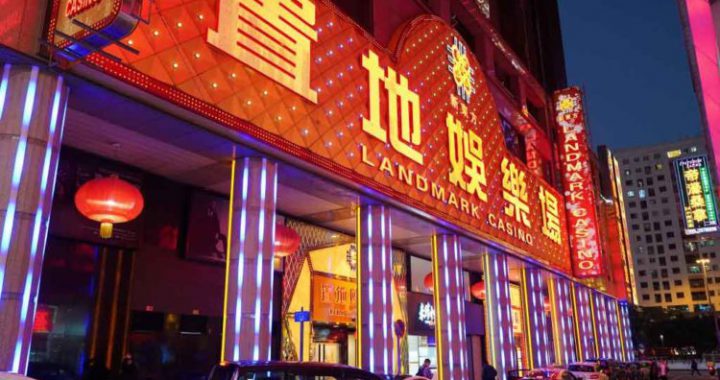 澳门置地广场赌场的夜景特写，建筑外墙有巨大的中文“置地娛樂場”霓虹灯招牌，夜间灯光璀璨，有多辆出租车停靠在入口处。