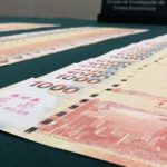 桌面上整齐摆放着多张中国银行（香港）发行的 1000 港元钞票，用于展示货币兑换或查获的赃款。
