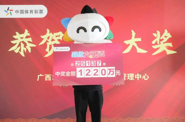 中国体育彩票吉祥物展示超级大乐透第25137期中奖金额1220万元的巨额支票，南宁老彩民以18元复式追加票获得此奖。