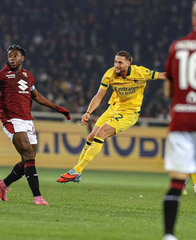 AC米兰球员(黄衣)在比赛中带球,与都灵(Torino)球员(红衣)进行激烈对抗,反映意甲或足球比赛的强度。