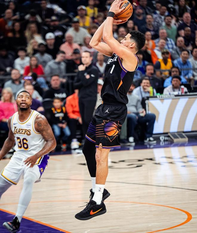 菲尼克斯太阳队球星德文·布克(Devin Booker,1号)身穿黑色球衣在比赛中跳投出手,身后是湖人队球员(背号36)的防守。