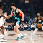 NBA比赛中波特兰开拓者球员持球进攻，中国球员参与挡拆对位克利夫兰骑士，现场观众气氛热烈