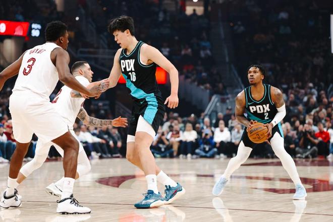 NBA比赛中波特兰开拓者球员持球进攻，中国球员参与挡拆对位克利夫兰骑士，现场观众气氛热烈