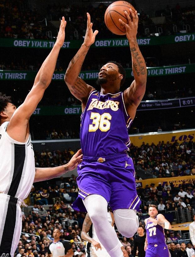 湖人隊球員（紫色球衣，36號）在 NBA 比賽中上籃得分，手臂上有紋身，對手（馬刺）球員在一旁進行防守。