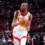 休斯顿火箭队超级巨星凯文·杜兰特（Kevin Durant）身穿白色球衣，在 NBA 比赛中持球进攻，周围是观众席背景。