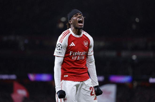 阿森納球員(紅白色球衣,20號)在足球比賽中大聲吶喊慶祝,背景是黑夜中的球場燈光,展現激情。