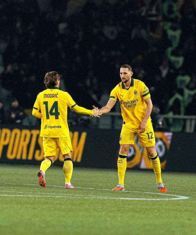 AC米兰两名球员(黄衣,号码14和12)在场上互相击掌或握手,展现球员间的配合与默契。