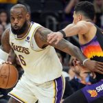洛杉矶湖人队球星勒布朗·詹姆斯（LeBron James，6号）身穿白色球衣在比赛中运球，面前是菲尼克斯太阳队球员的防守。