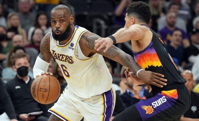 洛杉矶湖人队球星勒布朗·詹姆斯（LeBron James，6号）身穿白色球衣在比赛中运球，面前是菲尼克斯太阳队球员的防守。