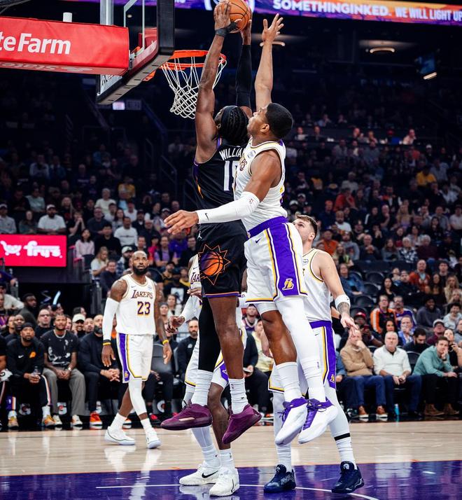 菲尼克斯太阳队球员(左,背号1)与洛杉矶湖人队球员(右)在高高跃起争抢篮板或试图扣篮,下方可见勒布朗·詹姆斯(背号23)。