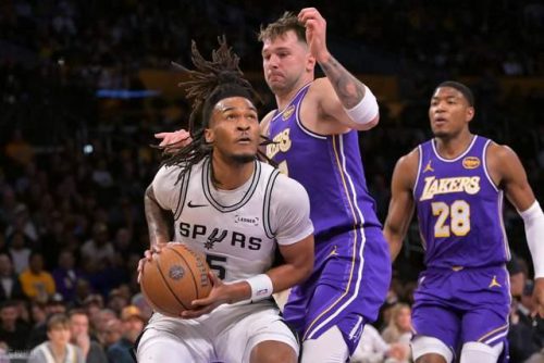 NBA 球星詹姆斯（LeBron James，23號）身穿湖人隊紫色球衣，在比賽中進行跳投，現場觀眾環繞，體現比賽焦點。