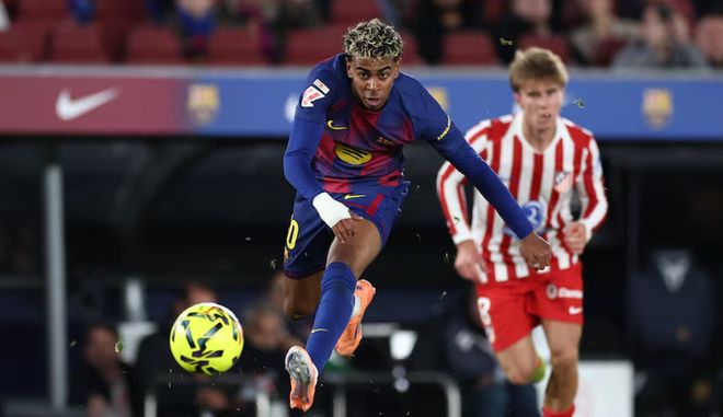 巴塞羅那球員在西甲比賽中運球推進，身後有馬德里競技球員追防。