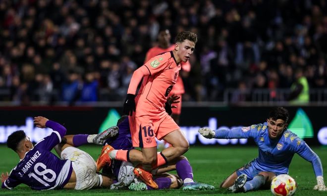 巴塞罗那球员（身穿橙色球衣，背号16）在国王杯比赛中带球突破，周围是倒地的防守球员（紫色球衣）和守门员。