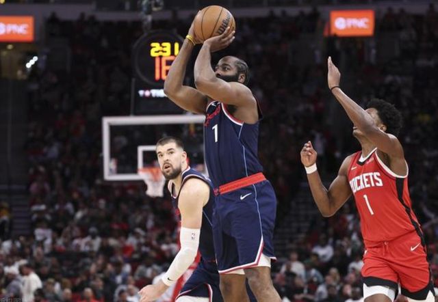 NBA 比賽中,一名藍色球衣球員高位跳投,面對 Houston Rockets 防守球員干擾,呈現激烈攻防瞬間。